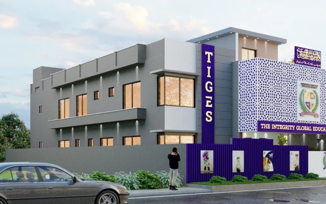 TIGES campus building at dusk: a lit vertical TIGES sign in purple and gold, the patterned facade with the crest, the school name across the front and a branded boundary wall
